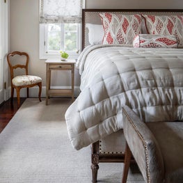 Bedroom w/ roman shades, hair-on hide bench, and coral and camel Euro shams
