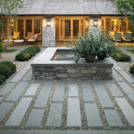 Stone fountain set within stone and gravel paving in home's central courtyard.