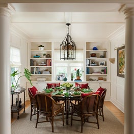 This white dining room backdrop has rattan chairs surrounding a round table.