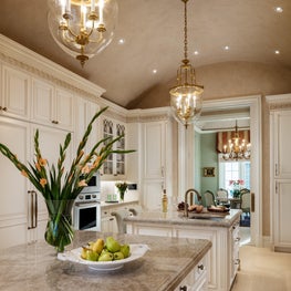The brass lighting fixtures add glamour to this white custom kitchen.