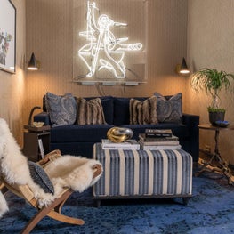 Penthouse television room with suede covered walls and modern neon sculpture