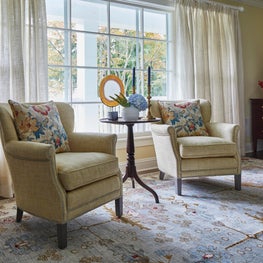 Glenview Foyer. Pair of club chairs in chamois linen and contrasting nailheads on light blue oriental rug.