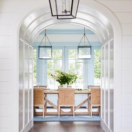 Blue and white dining room with painted trim and rattan chairs