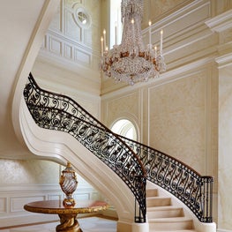 Bronze and gold leaf stair railing in a paneled hall with stenciled walls