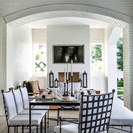 Portfolio: An ourdoor dining area with black and white chairs and outdoor TV.