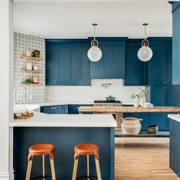 Blue and white kitchen with blue cabinets, patterned concrete tile backsplash.