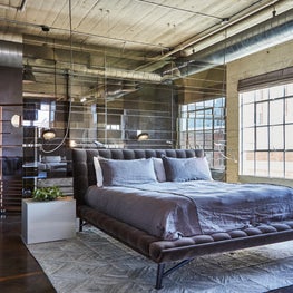 Bedroom space with all-glass panel headboard doubling as a screen/partition