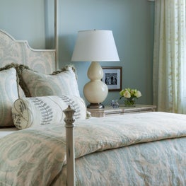 Custom bedding adds visual interest and complements the design of the bedroom. 