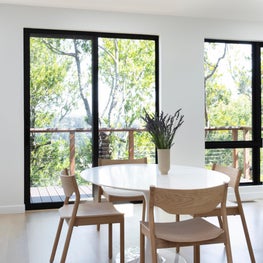 Dining area with balcony, skylights, light wood seating, and drum chandelier