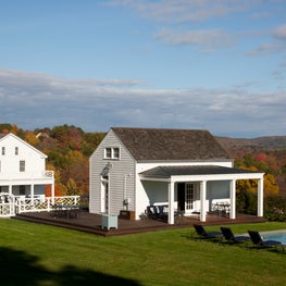 Upstate NY farmhouse exterior with pool house in foreground.
