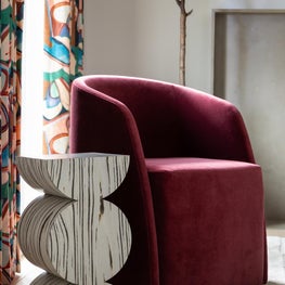 Portfolio: A curved burgundy lounge chair, patterned drapery, and a sculptural accent table introduce rich color and texture to this study.