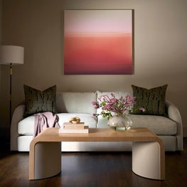 Portfolio: A curved sofa is paired with a sculptural oak cocktail table, tonal artwork, and soft florals to create a serene lounge within the primary suite.