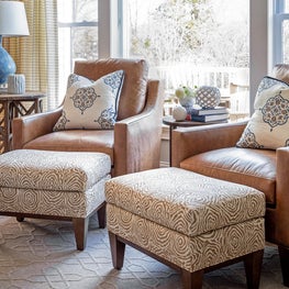 Family room camel leather arm chairs w faux bois printed linen ottomans