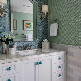 This bathroom is adorned in vibrant turquoise wall tiles and patterned wallcovering.