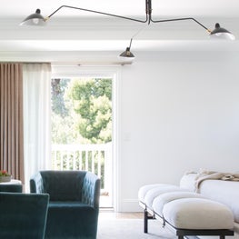 Show-stopping mid-century chandelier and teal chair in luxurious master bedroom.