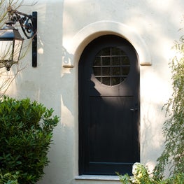 Arched Wood Entry Door in Stucco Wall with Antique Lantern Sconce