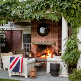 Trellis-covered Outdoor Living Space with Fireplace and Philippe Starck Chairs