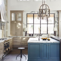 High-ceilinged kitchen with blue island cabinets, exposed beams