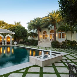 Lavish backyard views of the pool with stone tiled patio and pool house.