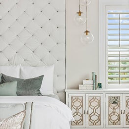 Master bedroom with tufted wall and glass orb pendant lighting w/gold finishes.