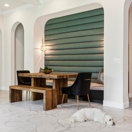 Breakfast nook w/ upholstered wall framed in decorative arches & beamed ceiling 