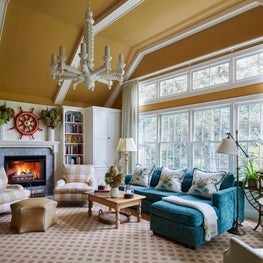 Glenview Family Room. Teal, tan and red scheme with white fireplace cabinetry, beamed ceiling & large chandelier.
