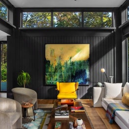 Modern living room with black paneled walls, low coffee table, vintage seating