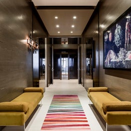 Moody dark wood panels in this foyer invite you past the glass front doors  