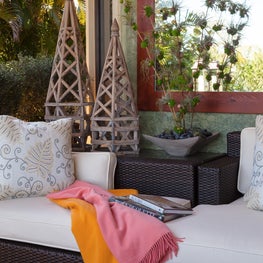 A cozy white cushioned rattan sofa for a relaxing read.