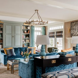 Living room with blue velvet matching sofas and robins egg built-in bookshelves