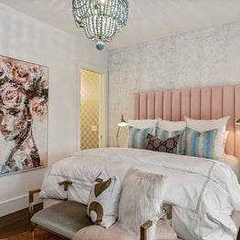 Glam, colorful bedroom with speckled wallpaper, beaded chandelier and wall art.