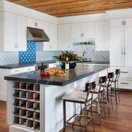 Polished nickel bar stools upholstered in white leather provide a modern touch.