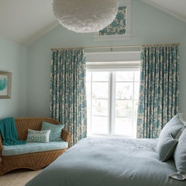 Blue bedroom with round white chandelier and coastal motifs
