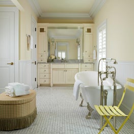 A spa-like bathroom in pale yellow equipped with a white free-standing tub.