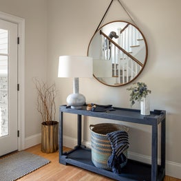 Navy entry table, Arteriors table lamp, colorful basket and round mirror