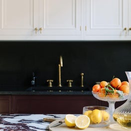 European Style Kitchen with two tone cabinets, marble island, and brass fixtures