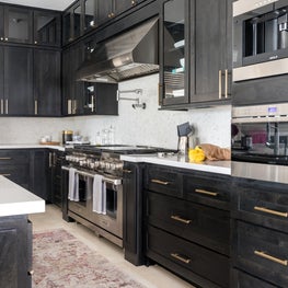 Portfolio: A gorgeous and functional kitchen with black stained cabinets, white floors, gold drawer pulls, and stainless steel appliances