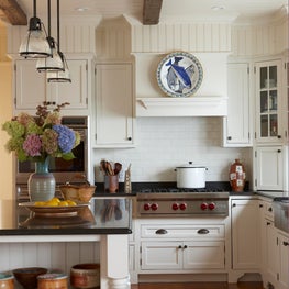 A classic kitchen has a country vibe by adding pottery and a striped area rug.