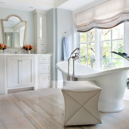 American Lodge Master Bath. Neutral spa colors with arched mirror, slipper tub & orange accent flowers.