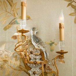 A close up on mirrored sconces designed to echo a powder bath's chinoiserie bird motif