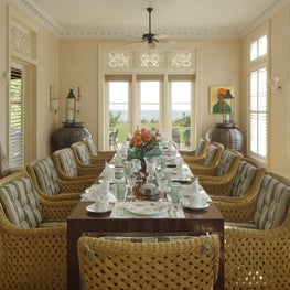 An airy oceanfront Dining Room in Palm Beach.  Carved teak window transoms