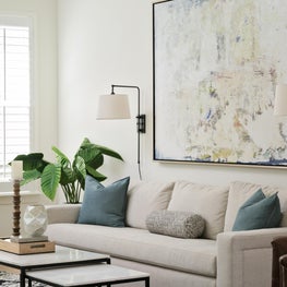 Creamy neutral living room with contemporary statement art & symmetrical sconces