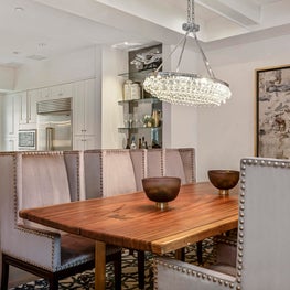 Crystal chandelier hanging from beamed ceiling; nailhead dining chairs, wall art