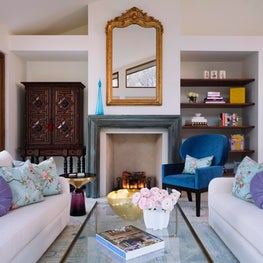 A Bright Blue Chair and Gilded Mirror a Join Spanish Colonial Armoire and Custom Sofas in this Elegant Living Room
