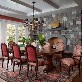 Lake Geneva Dining Room. Partition fireplace with gray & coral stone, coral fabrics and dark wood finishes.