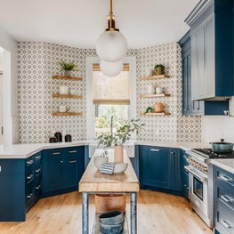 Blue and white kitchen with blue cabinets, patterned concrete tile backsplash.