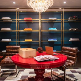 Jewel Tone Office with red lacquer desk, mid century chairs, & brass bookshelves