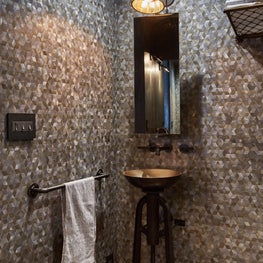 Powder room with bronze vessel sink with an industrial pedestal base