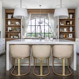 Portfolio: A white kitchen design with leather stools and hidden refrigerator.