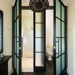 Tile Shower and Water Closet behind Steel and Glass Doors with Black Stone Floor